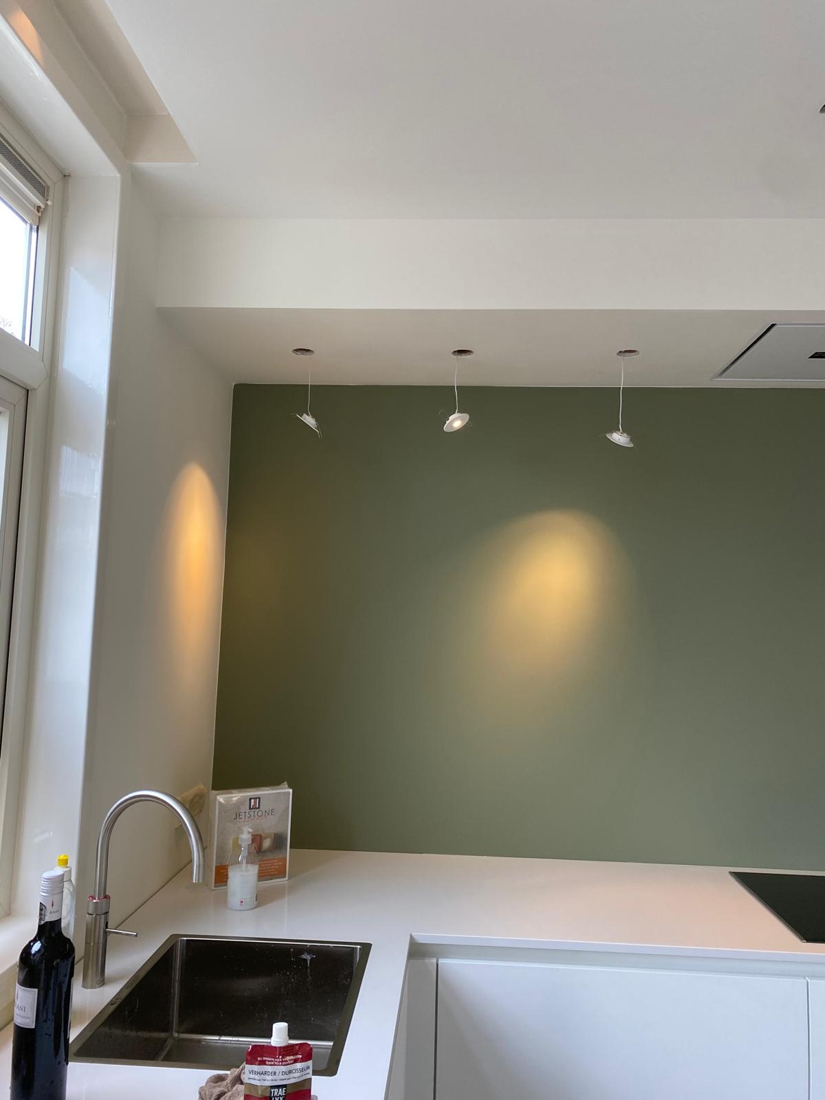 Keuken met saliegroene wand en strak wit plafond met inbouwspots