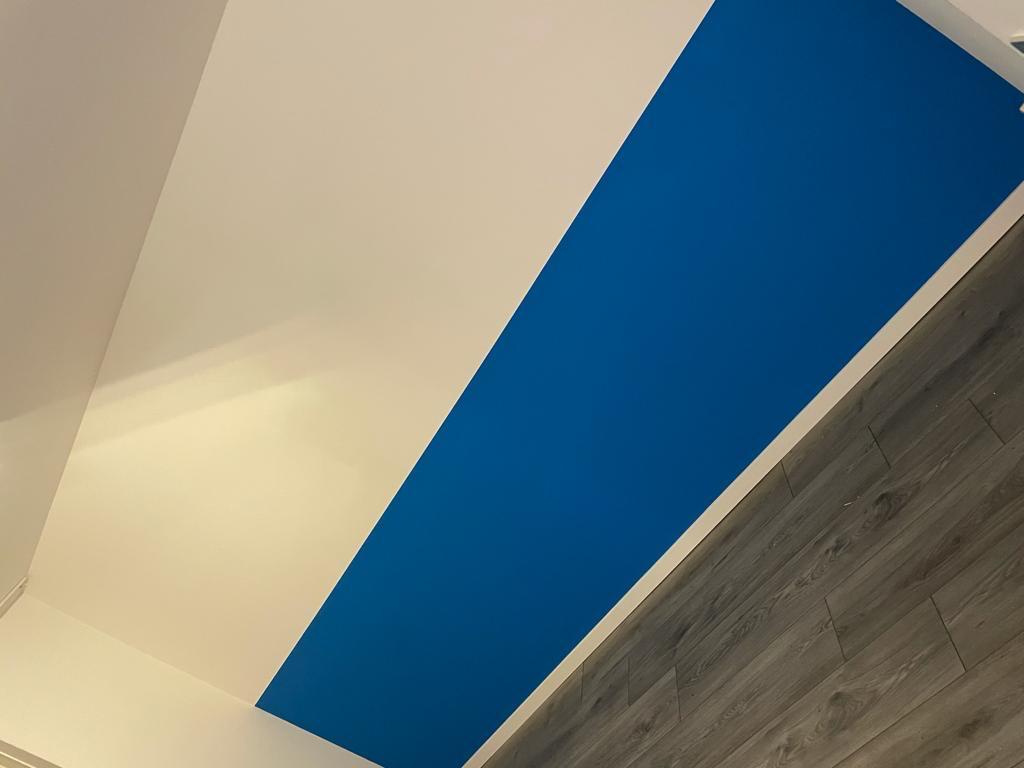 Strak geschilderde wand in wit en kobaltblauw met houten vloer